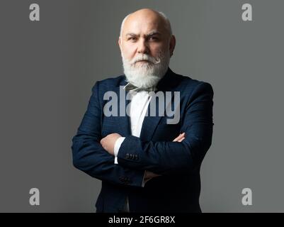 Uomo anziano in abito, uomo di 60 anni. Uomo d'affari maturo che guarda la telecamera isolata su grigio. Foto Stock