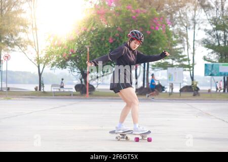 Donne asiatiche su skates bordo all'aperto nella bella giornata estiva. Le giovani donne felici giocano a surfskate al parco l'ora del mattino. Attività sportive stile di vita conce Foto Stock