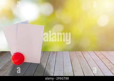 Carta bianca vuota su tavolo di legno con sfondo verde bokeh. Carta vuota per schede di nome su legno uso per testo o disegno. Con spazio per la copia Foto Stock