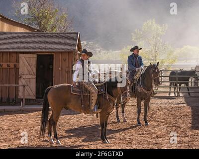 Un giovane e attraente giradino da cowgirl e un cowboy sui loro cavalli in un ranch vicino Moab, Utah. Foto Stock