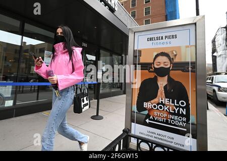 New York, Stati Uniti. 31 Marzo 2021. Una donna cammina oltre l'ingresso al Chelsea Piers Fitness nel quartiere Brooklyn di New York City, NY, 31 marzo 2021. I membri sono tenuti a indossare sempre maschere, in quanto le classi sono tenute piccole per mantenere la distanza sociale. (Foto di Anthony Behar/Sipa USA) Credit: Sipa USA/Alamy Live News Foto Stock