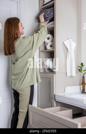 Le mani della donna mettono ordinatamente o espongono un pulito arrotolato su asciugamani bianchi fatti da cotone organico. Foto Stock