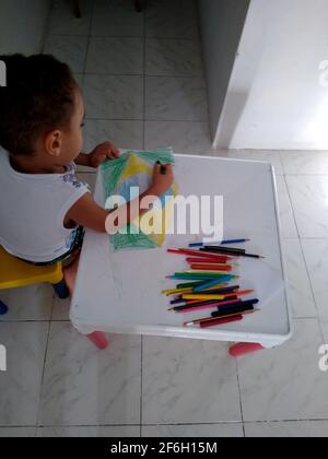 salvador, bahia / brasile - 18 novembre 2020: Il bambino si vede dipingere un disegno della bandiera del Brasile durante le attività scolastiche. Foto Stock