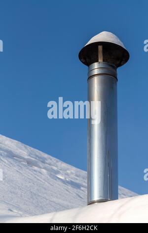 Camino su un tetto innevato di una casa privata. Foto Stock