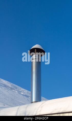 Camino su un tetto innevato di una casa privata. Foto Stock