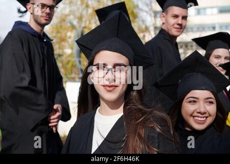 Istruzione, graduazione e concetto di persone - gruppo di felice gli studenti internazionali in mortaio e schede di corso di laurea gli abiti con diplomi Foto Stock