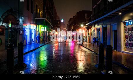 Un singolo visitatore cammina lungo Bourbon Street a New Orleans, Louisiana, in una notte piovosa nel marzo del 2021 dopo una grande tempesta. Foto Stock