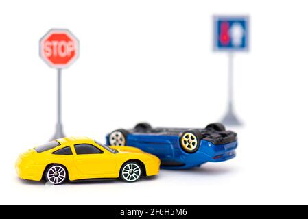 Incidente con due auto giocattolo e segno stop isolato su bianco. Immagine concettuale sull'incidente stradale Foto Stock