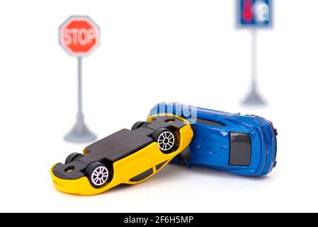 Incidente con due auto giocattolo e segno stop isolato su bianco. Immagine concettuale sull'incidente stradale Foto Stock