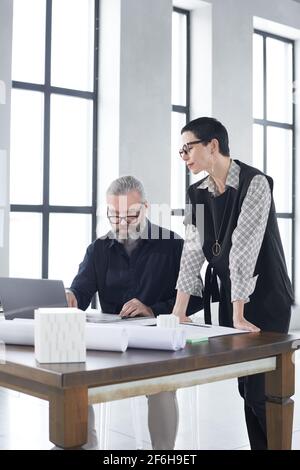 Due architetti discutono di progetto e progetto al tavolo di lavoro in squadra in ufficio Foto Stock