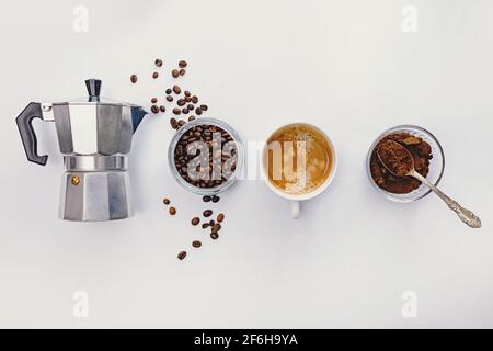 Composizione piatta con moka pot, caffè in grani e espresso caldo fresco in una tazza. Foto Stock