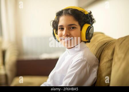 Ragazzo arabo che ascolta la musica con le cuffie a casa Foto Stock