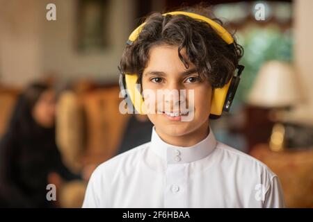 Ragazzo arabo che ascolta la musica con le cuffie a casa Foto Stock