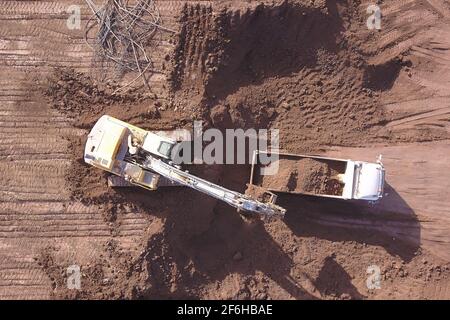 Escavatore che carica il terreno su un dumper in un nuovo sito di sviluppo. Foto Stock