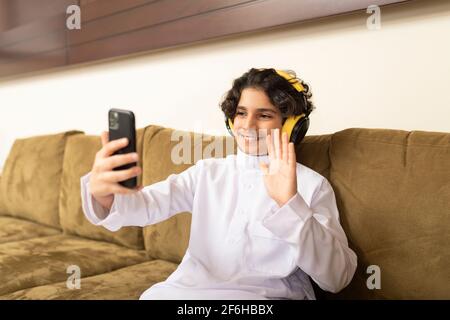 Ragazzo arabo a casa con cuffie e cellulare Foto Stock