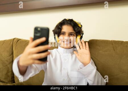 Ragazzo arabo a casa con cuffie e cellulare Foto Stock