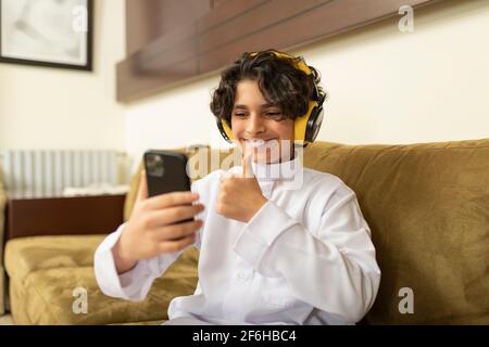 Ragazzo arabo a casa con cuffie e cellulare Foto Stock