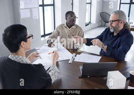 Gruppo di architetti seduti al tavolo e che discutono del progetto hanno una riunione in ufficio Foto Stock