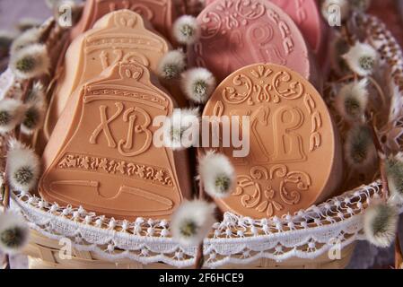 Delicato sapone pasquale fatto a mano in un cesto di vimini e una varietà di decorazioni pasquali. Foto Stock