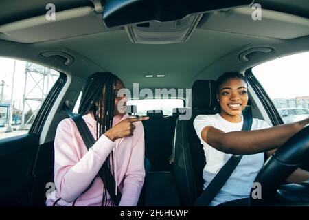 Giovani amiche africane che si divertono a guidare nel traffico cittadino Foto Stock