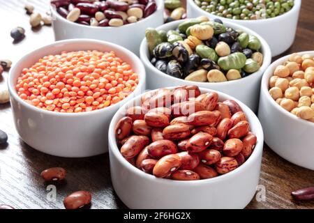 Assortimento di legumi in ciotole su un tavolo di legno Foto Stock