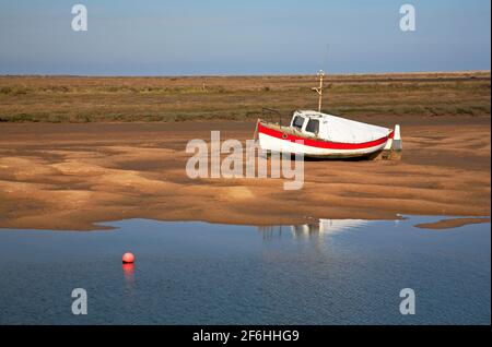 Una vista di una barca da pesca costiera spiaggiata in acque basse a Overy Creeek nel Nord Norfolk a Burnham Overy Staithe, Norfolk, Inghilterra, Regno Unito. Foto Stock