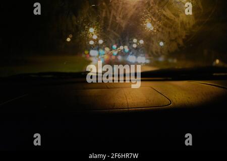 le luci offuscate provenienti dai fari dell'auto e i segnali durante la guida durante la notte piovosa. Durante le inondazioni del marzo 2021 a Sydney Foto Stock