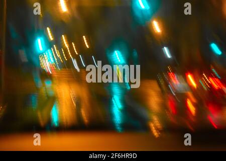 le luci offuscate provenienti dai fari dell'auto e i segnali durante la guida durante la notte piovosa. Durante le inondazioni del marzo 2021 a Sydney Foto Stock