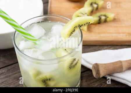 Kiwi brasiliano caipirinha in un bicchiere con ghiaccio con fette di frutta su tavola di legno . Foto Stock