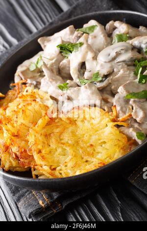 Zurcher Geschnetzeltes fatto di strisce di vitello a fette, vino bianco, funghi, panna e merletto servito con rosti in primo piano sul piatto. Ve Foto Stock