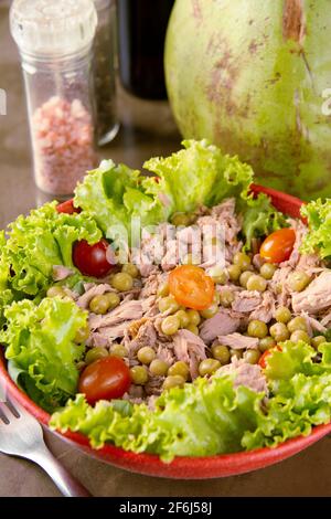 Insalata su ciotola colorata, sale, pepe e cocco verde su sfondo di pietra. Foto Stock