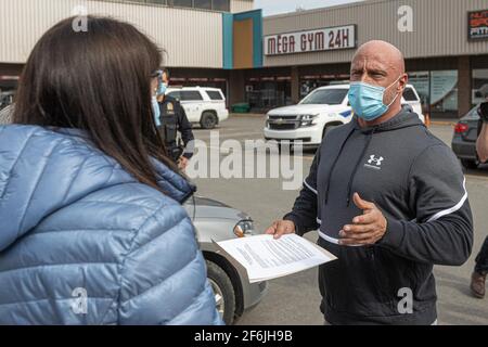 I dipendenti di SECURITE Publique danno ad un formatore di Mega Gym 24h i documenti ufficiali per un arresto obbligatorio della sua palestra a seguito di un'epidemia importante di COVID 19 a Quebec City, 31 marzo 2021. Foto Stock