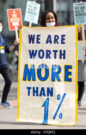 Londra, Regno Unito. 1 aprile 2021. Un manifestante che ha un banner con la scritta "noi abbiamo un valore superiore all'1%". I lavoratori dell’NHS hanno protestato per la proposta di un aumento salariale dell’1% da parte del governo al di fuori del St Thomas’ Hospital, Westminster Bridge Road, Londra, Regno Unito. Credit: Joshua Windsor/Alamy Live News Foto Stock