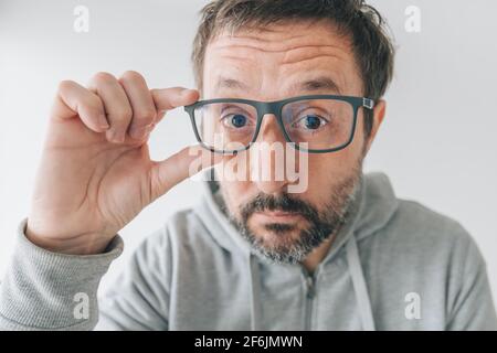 Uomo che prova fuori nuovo paio di occhiali, facendo faccia divertente, primo piano con fuoco selettivo Foto Stock