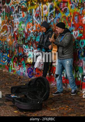 Una foto di due artisti di strada che si esibiscono di fronte al muro di John Lennon (Praga). Foto Stock