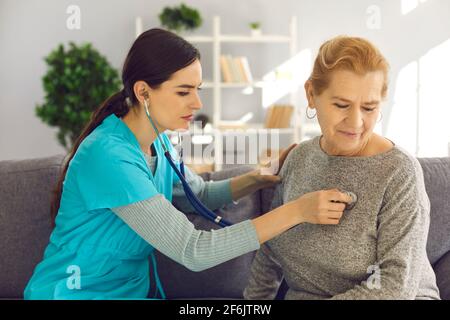 Medico che controlla il cuore o i polmoni del paziente anziano durante la visita domestica o controllo in clinica Foto Stock