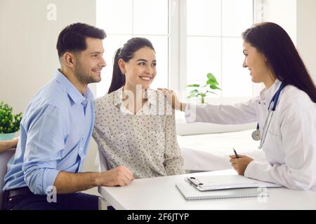 Dottore di sesso femminile che consulta i pazienti di coppia giovane in clinica di fertilità circa IVF o IUI. Foto Stock