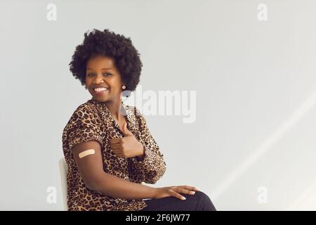 Donna afroamericana che mostra i pollici in su approvando il ritratto dello studio di vaccinazione Foto Stock