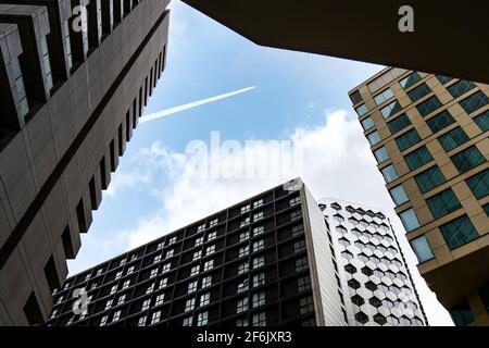 Birmingham England 3.2.2020 - guardando in alto attraverso grattacieli torre dell'ufficio blocco in aereo jumbo jet volo sopra i sentieri nel angolo cielo blu basso Foto Stock