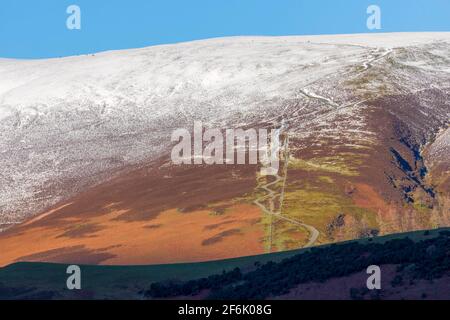 Skiddaw, Lake District National Park, Cumbria. Gli escursionisti possono essere visti sul ripido sentiero per la cima anche in una giornata innevata in dicembre. Foto Stock