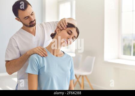 Osteopata professionale durante il lavoro che fissa il collo delle donne Foto Stock