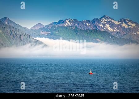 Nebbia che sale sulle montagne in Alaska, visto dall'acqua aperta Foto Stock
