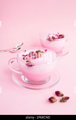 Latte di luna di rosa in due tazze sulla superficie rosa. Posizione verticale. Foto Stock
