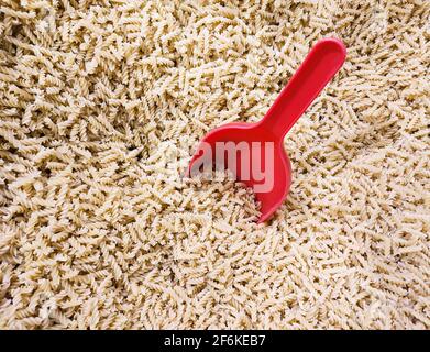 Un mucchio di pasta italiana cruda di rotini cruda non cotta con scoop top visualizza Foto Stock