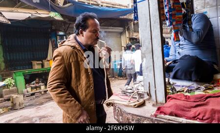 Kolkata, Bengala Occidentale, India - Gennaio 2018: Un uomo indiano che illumina una sigaretta in una stalla paan sulla strada per le strade della città di Kolkata. Foto Stock