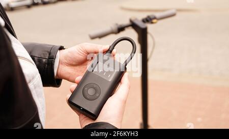 Un uomo pompa aria nella ruota di uno scooter elettrico utilizzando un dispositivo speciale. Foto Stock