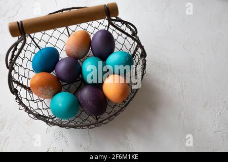 Uova di Pasqua in una ciotola in blu, turchese, porpora e arancio, e brioche a forma di coniglietto pasquale. Foto Stock