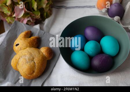 Uova di Pasqua in una ciotola in blu, turchese, viola e arancione. Foto Stock