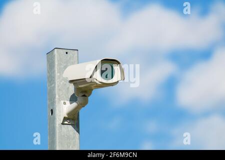 Telecamera di sorveglianza CCTV video installata su un palo di ferro con cielo blu e nuvole sullo sfondo e situata a Lugano, Svizzera Foto Stock