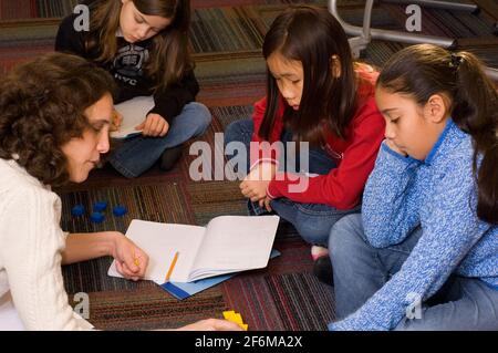 Scuola elementare indipendente grado 4 età 9-10 insegnanti di matematica femminile lavorare con due ragazze che usano manipolativi per lavorare sulla matematica concetti Foto Stock